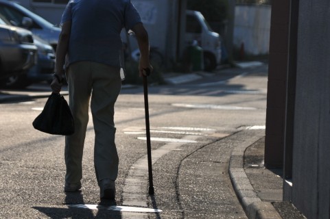 つえをついて歩く女性